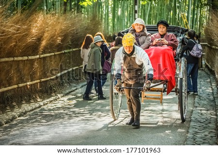 KYOTO, JAPAN - NOVEMBER 19: Rickshaw in Kyoto, Japan on November 18, 2013. Unidentified man with a rickshaw and tourists at Chikurin-no-michi, famous bamboo grove near Tenryuji Temple