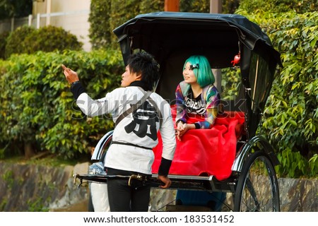 KYOTO, JAPAN - NOVEMBER 20: Rickshaw in Kyoto, Japan on November 20, 2013. Unidentified rickshaw driver gives a piece of information to his passenger about the place where they made a stop