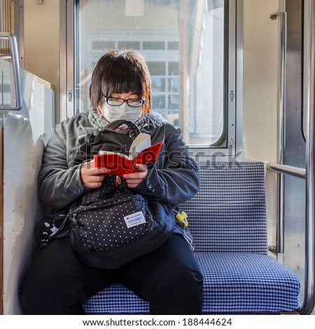 Yamanashi, Japan - November 22 2013: Unidentified female wears a mask to prevent people from catching her flu on a train