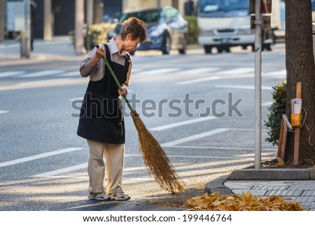 TOKYO, JAPAN - NOVEMBER 26: Japanese worker in Tokyo, Japan on November 26 , 2013. Unidentified Japanese female worker cleans a street at Chuo city area