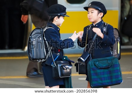 TOKYO, JAPAN - NOVEMBER 22: Japanese Student in Tokyo, Japan on November 22, 2013. Unidentified little Japanese students wait for a train to school in the morning at Tokyo station