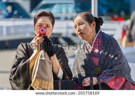 TOKYO, JAPAN - NOVEMBER 26: Senior women in Tokyo, Japan on November 26, 2013. Unidentified Japanese women check compact camera after taking photos at Tokyo Station