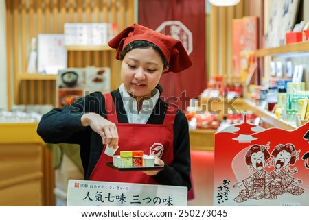 KYOTO, JAPAN - OCTOBER 23: Nishiki Market in Kyoto, Japan on October 23, 2014. Unidentified Japanese shopkeeper prepares food sample for her customers