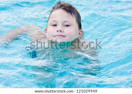 a little boy bathes in a pool in blue clean water