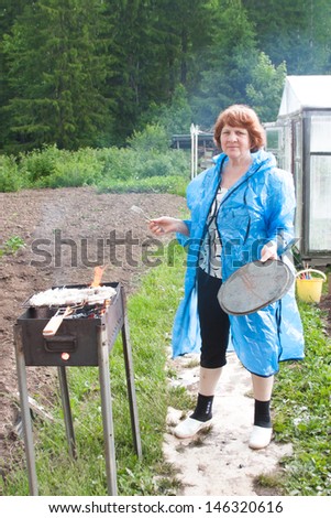 an elderly woman cooks on nature