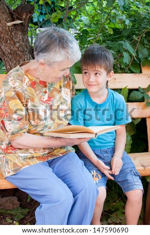 a great-grandmother reads a book to the great-grandchild in a garden