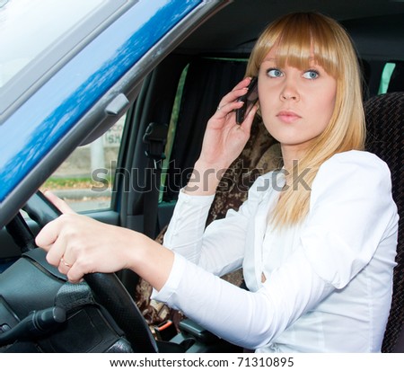 charming beautiful woman after the helm of car with a telephone in hands