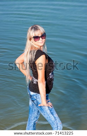 a young beautiful woman stands in water on the riverside