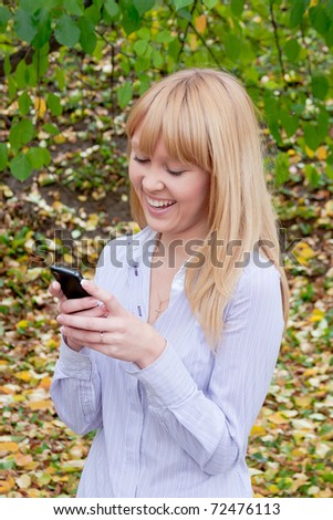 young beautiful woman in an autumn park with a telephone  in hands