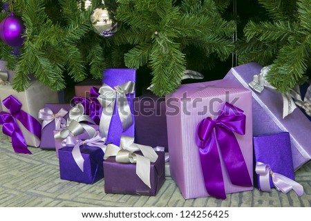 Photo of luxury gift boxes under Christmas tree, New Year home decorations,  wrapping of Santa presents, festive fir tree decorated with garland, baubles and angels, traditional celebration