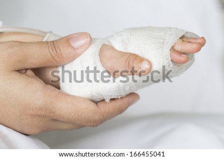 Closeup of nurse holding patients hand in hospital