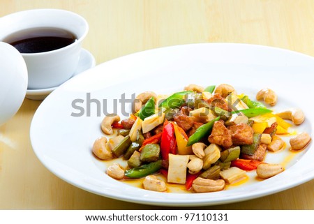 Chicken with cashew nuts, chili, capsicum and snow peas on a bamboo mat with chop sticks
