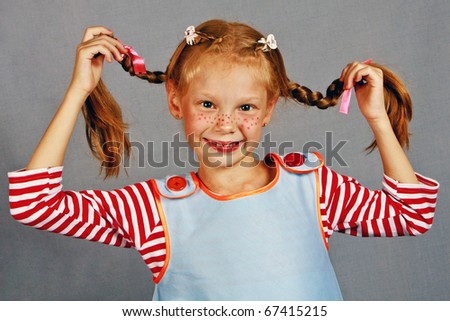 Red-Haired girl with upward braids making face / Whimsical, color photo of a happy, red-haired girl with upward braids and a smile!