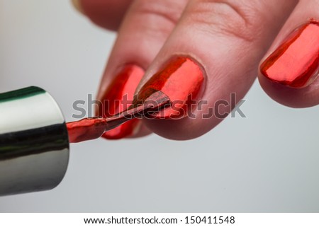 Painting female fingernails with red nail polish