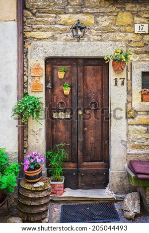 ITALY - JUNE 23, 2014: Windows and doors in an old house decorated with flower pots and flowers