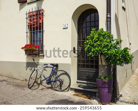 TUSCAN, ITALY.23 June 2014. bike loaded with flowers standing in front of an old door in a traditional Italian medieval city center. Tuscany, Italy.