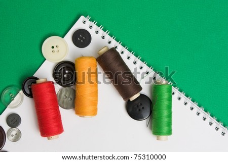thread with a needle and buttons on the background of the notebook