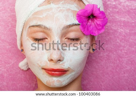 Cute young girl getting pampered with a deluxe spa treatment including facial mask.