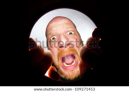 frightened man looking in a hole
