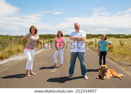 A happy family pose for a photo on a quiet road in the country