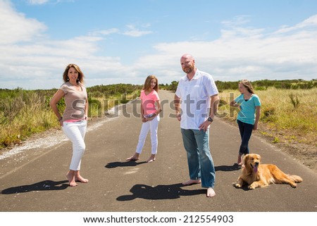 A happy family pose for a photo on a quiet road in the country
