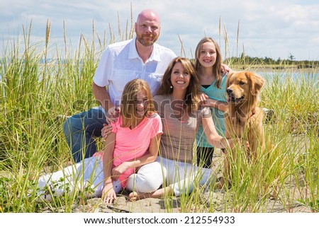 A happy American family on vacation at the beach with their golden retriever dog