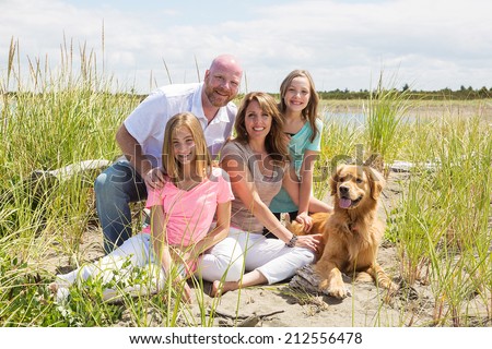 A happy American family on vacation at the beach with their golden retriever dog