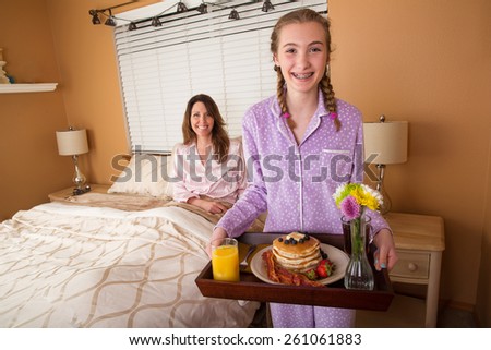 Teenage girl serving her Mom breakfast in bed on Mothers Day