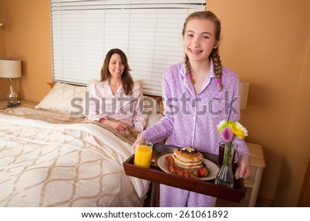 Teenage girl serving her Mom breakfast in bed on Mothers Day