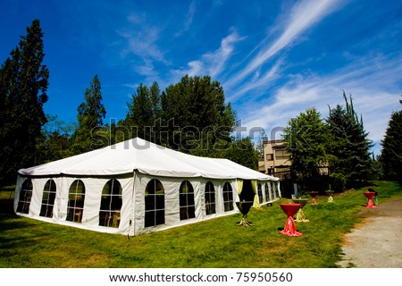 A large tent outside under a cloudy blue sky
