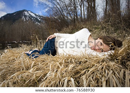 a pretty woman laying down and taking a nap outside in tall grass.