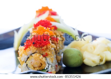 Red and orange fish eggs or tobiko on crunchy seafood sushi rolls at an Asian food restaurant.