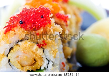Red and orange fish eggs or tobiko on crunchy seafood sushi rolls at an Asian food restaurant.