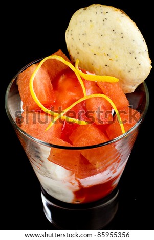 Fresh fruit cup with watermelon, lemon zest, ice cream and a cookie.