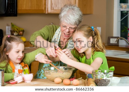 Happy Family featuring a friendly Grandma baking cookies in a home kitchen with her two Grandchildren.