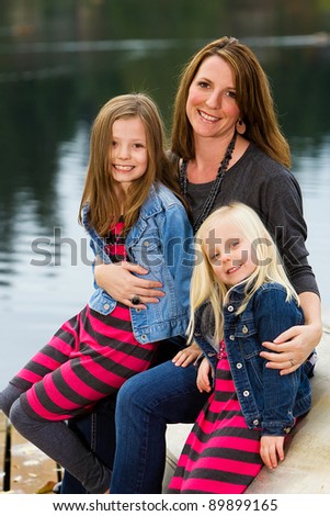 A pretty Mother and her two daughters outside at a lake.