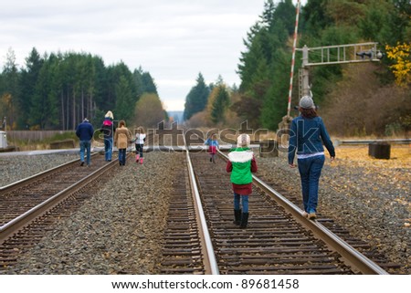 Group of people walking down railroad tracks.
