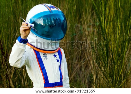 Young boy in an astronaut suit playing with a toy airplane.