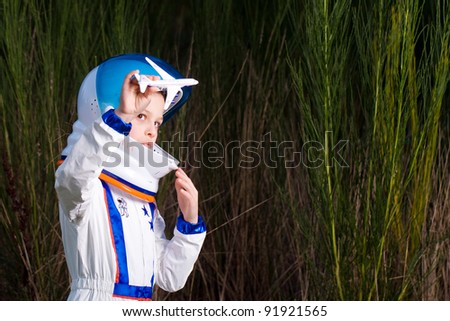 Young boy in an astronaut suit playing with a toy airplane.