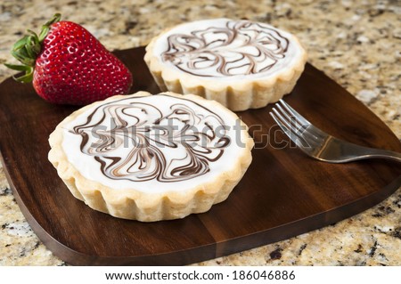 Two white chocolate tarts on a granite background