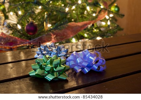 Three Christmas bows sitting on a table in front of a decorated tree