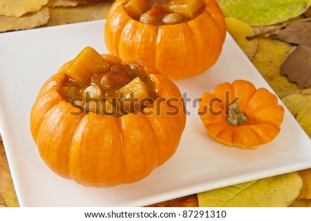 Mini Pumpkins filled with pumpkin soup surrounded by fall leaves