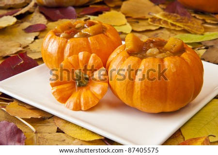 Pumpkin soup in mini pumpkin bowls with colorful fall leaves