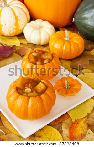 Mini Pumpkins filled with pumpkin soup surrounded by fall leaves
