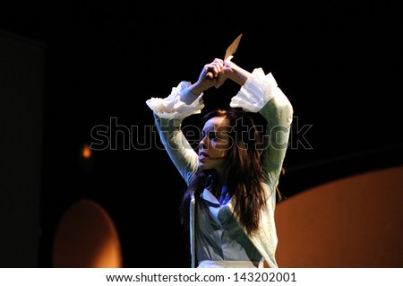 BARCELONA - JAN 13: An angry acttress of the Barcelona Theater Institute, plays with a knife in the hands in the comedy Shakespeare For Executives on January 13, 2013 in Barcelona, Spain.