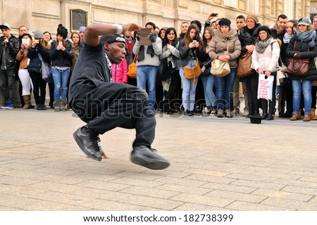 PARIS - MAR 1: People watch a homeless streetdancer doing breakdance and dance moves in the streets of Paris to earn some money on March 1, 2014 in Paris, France.
