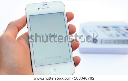 BARCELONA, SPAIN -Â?Â? APR 08, 2014: A male hand holding a white Apple Iphone device above and an Iphone case on the background, isolated in white background.
