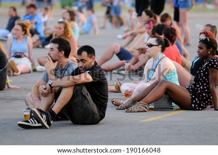 BENICASIM, SPAIN - JULY 19: People from the crowd (fans) watch a concert, sitting quietly on the floor at FIB  Festival on July 19, 2013 in Benicasim, Spain.