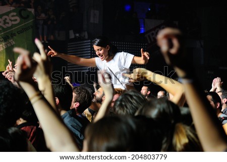 BARCELONA - MAY 16: A girl stands over the crowd in a concert at Razzmatazz discotheque on May 16, 2014 in Barcelona, Spain.
