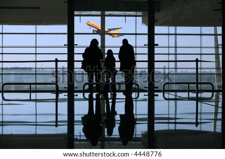 family looking to a airplane through the window in the airport